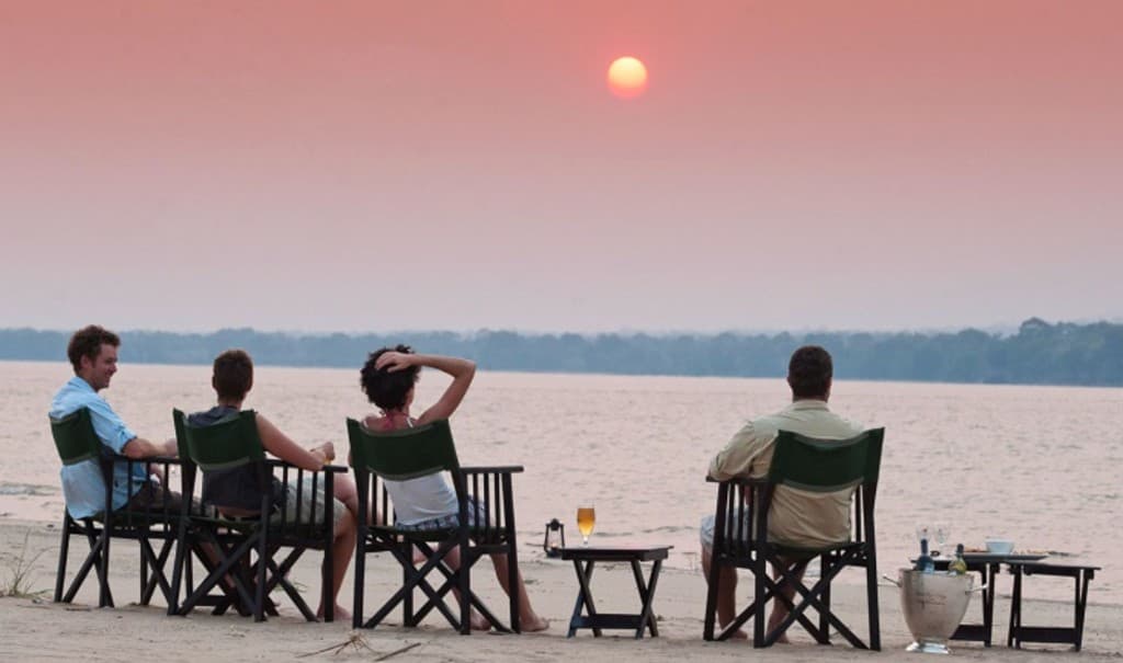 Travelers enjoying a riverside sundowner at sunset in Africa